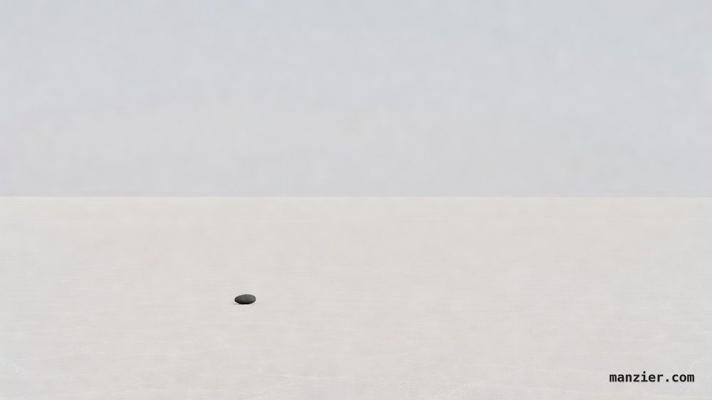 A vast pale salt flat under an enormous soft gray-white sky with a single small dark stone alone in the lower third, casting a short crisp shadow